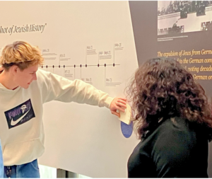 A high school student explores and interactive element on a timeline of Jewish history at JMM with the help of Chief Curator Molly Dubin.